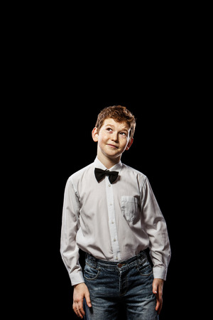 The red-haired boy looking up on a black background with a white shirtの写真素材