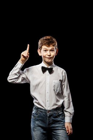 The red-haired boy on a black background with a white shirt holding thumbs upの写真素材