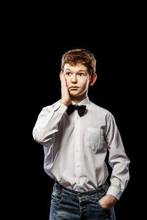 The red-haired boy on a black background with a white shirtの写真素材