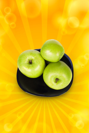 Three green apples on a black plate with a white backgroundの写真素材