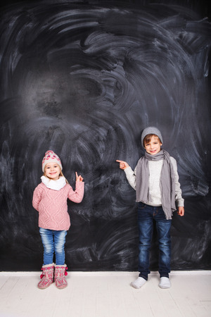 Beautiful boy and girl standing on a gray background. Background is well suited for drawing anything.の写真素材