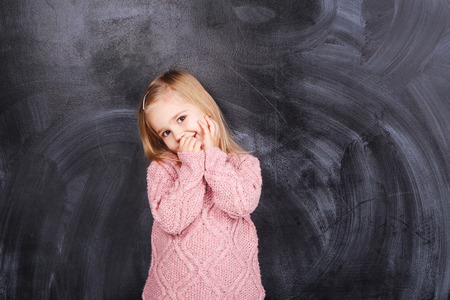 Cute little girl on a gray background in a pink sweaterの写真素材