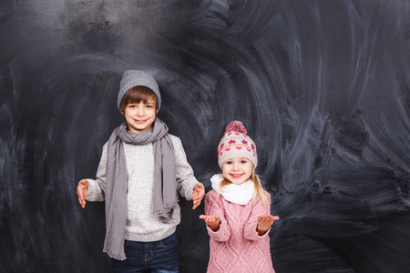 Beautiful boy and girl standing on a gray background. Background is well suited for drawing anything.の写真素材