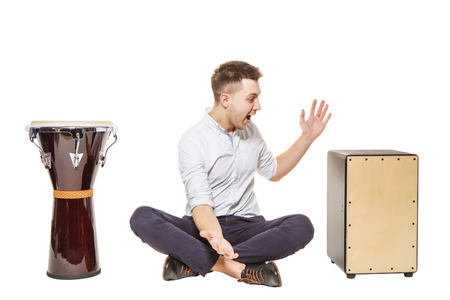 The guy between the djembe and Cajon on a white background does not know what to chooseの写真素材