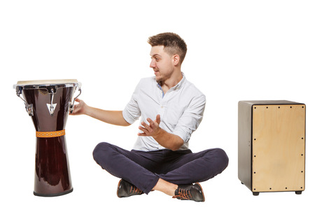 The guy between the djembe and Cajon on a white background does not know what to chooseの写真素材