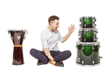 The guy between the djembe and drums on a white background does not know what to chooseの写真素材