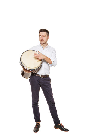 Young and handsome guy playing the djembe instrument on a white backgroundの写真素材