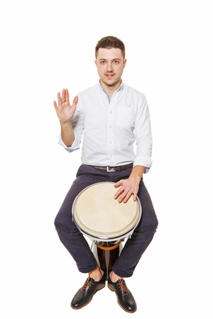 Young and handsome guy playing the djembe instrument on a white の写真素材