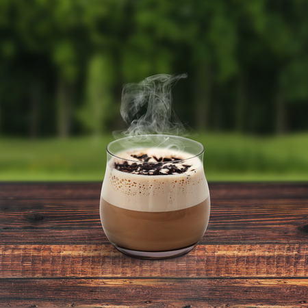 Cup of coffee on wooden table around treeの写真素材