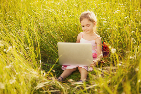 Little girl with laptop on natureの写真素材