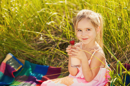 Little girl drink yogurt on picnicの写真素材