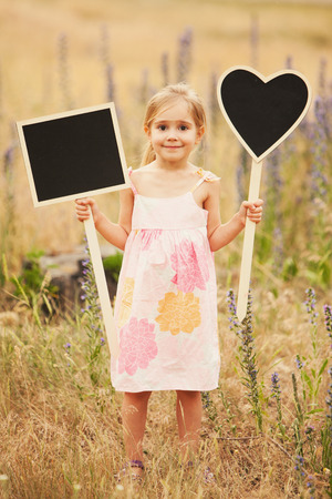 Cute little girl with plate love and square on natureの写真素材