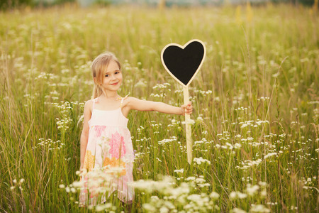 Cute little girl with plate love on natureの写真素材