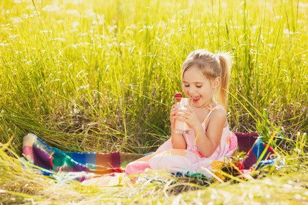 Little girl drink yogurt on the picnicの写真素材