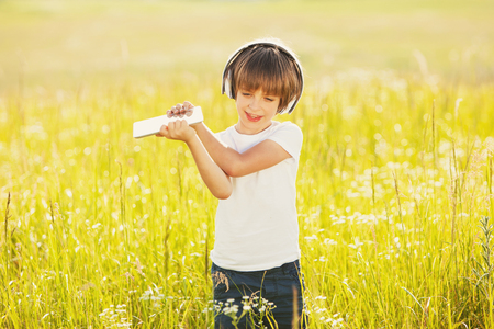 Little boy listening to music outdoors with tabletの写真素材