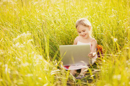 Little girl with laptop on natureの写真素材