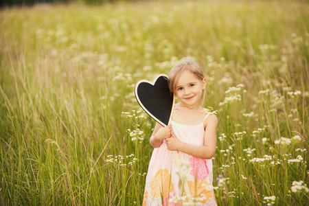 Cute little girl with plate love on natureの写真素材