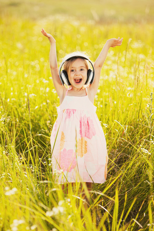 Happy little girl listening to music outdoorsの写真素材