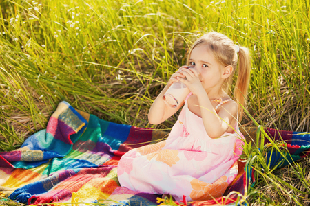 Little girl drink yogurt on picnicの写真素材