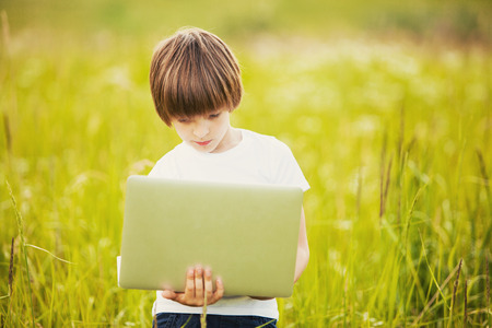Little boy with laptop on natureの写真素材