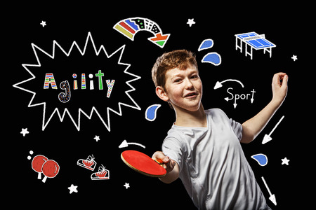 Boy playing table tennis on a black backgroundの写真素材