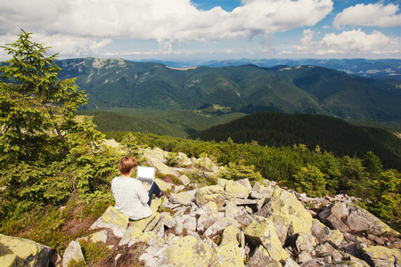 Woman sitting on the hill with laptopの写真素材