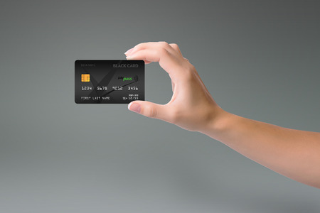 Isolated black credit card in woman hand on gray backgroundの写真素材