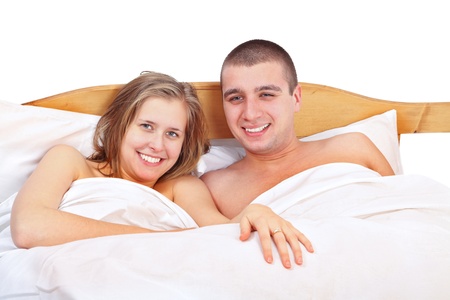 Happy young man and woman laying in bed smiling and loving each other.の写真素材