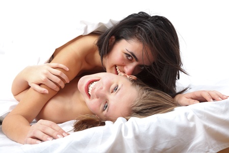 Attractive laughing girls in bed having fun.の写真素材