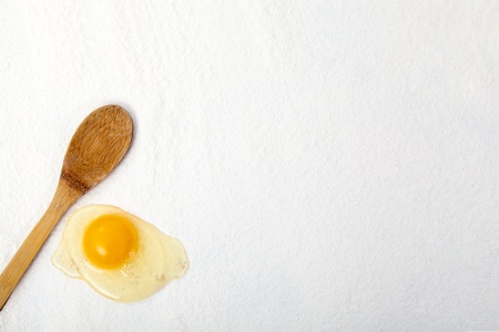 Egg and wooden spoon on the flour ont he table