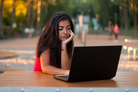 Beautiful girl outdoors thinking and using internet on her laptop.の写真素材