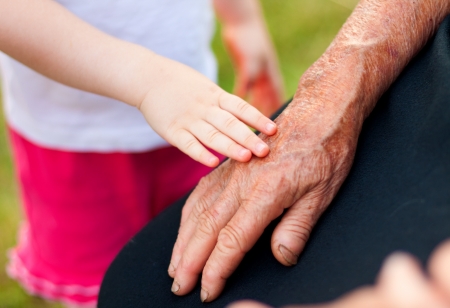 A little girl touching her grandmother's hand gently.の写真素材