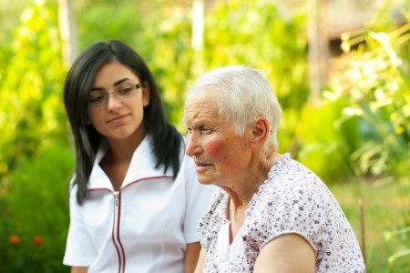 Old lady talking to the young nurse / doctor outdoors.の写真素材