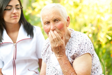 Sad elderly woman with her hand on her mouth.の写真素材