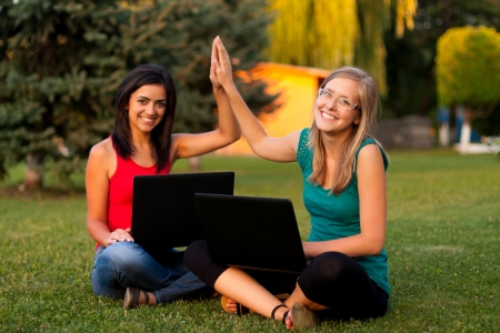Girlfriends with their laptops having good time outdoors.の写真素材