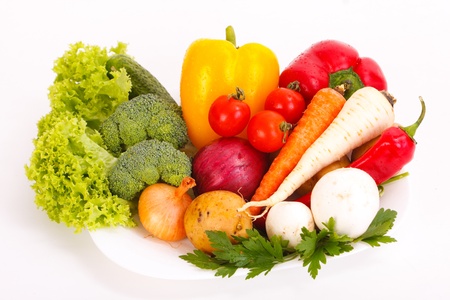 Different fresh vegetables with water drops on a plate isolated on white.の写真素材