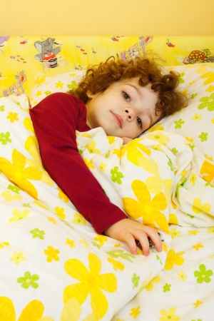 Little sick girl at home laying in her bed.の写真素材