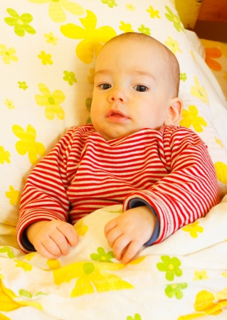 Cute baby boy laying in bed and  smiling.の写真素材
