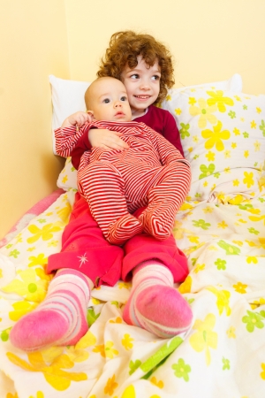 Little girl holding her baby brother on her lap.の写真素材