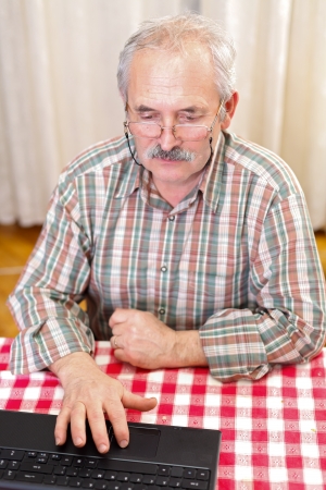 Elderly man using laptop sitting at home.の写真素材