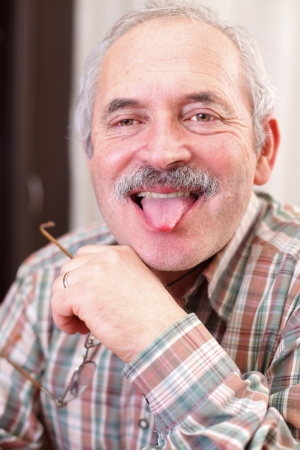 Portrait of a funny senior man shooting his tongue.の写真素材