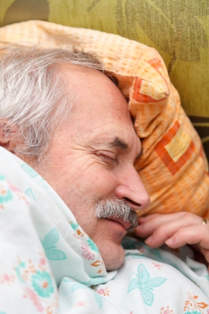 Elderly man laying peacefully in his bed smiling.の写真素材