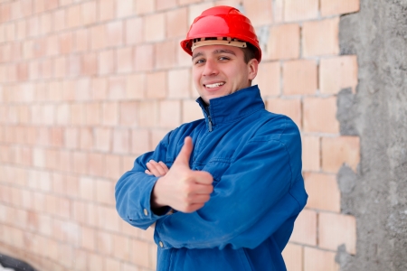Happy construction worker showing thumbsup next to an unfinished  brick wall.の写真素材