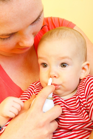 Mother using nose spray to cure her baby.の写真素材