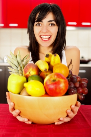 Young cute brunette girl holding a dish full of fruits beginning her diet.の写真素材