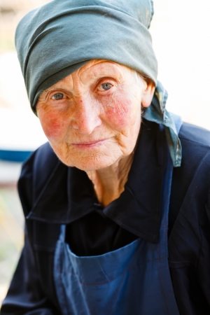 Portrait of an elderly rural lady with beautiful blue eyes and headscarf on at home.の写真素材