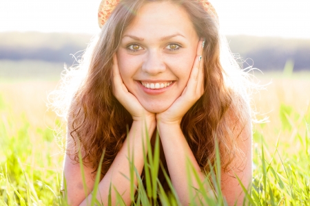 Beautiful lady smiling lovely sitting on grass with her head in hands.の写真素材