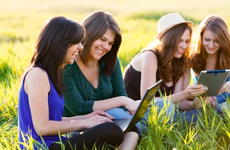 Beautiful students on grass using wireless internet on their laptops and tablets.の写真素材