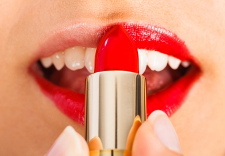 Lady applying gently red lipsitck on her lips.の写真素材