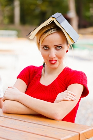 Student with book on head putting out her tongue being funny.の写真素材